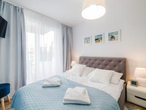 Un dormitorio con una cama grande con dos toallas encima. en Apartament Baltic Polanki Park Kołobrzeg, en Kołobrzeg 53 fotos más