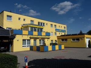 a yellow and blue building with a parking lot at Motel Am Highway in Althengstett