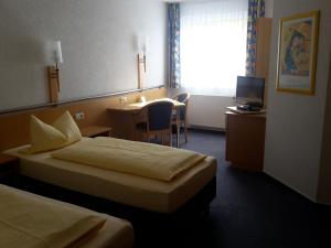 a hotel room with two beds and a table and a television at Motel Am Highway in Althengstett