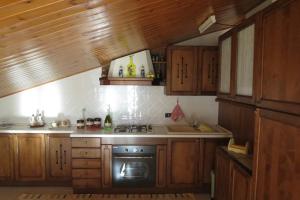 a kitchen with wooden cabinets and a stove top oven at Mansarda Stella sul Mare in Pollina