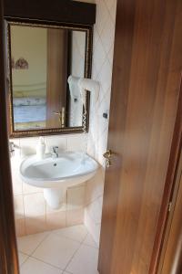 La salle de bains est pourvue d'un lavabo et d'un miroir. dans l'établissement Agriturismo L'Assiolo, à Miglionico