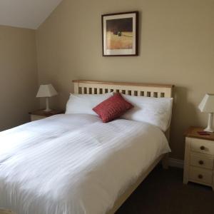 um quarto com uma cama branca e uma almofada vermelha em Greenway View B&B em Newport