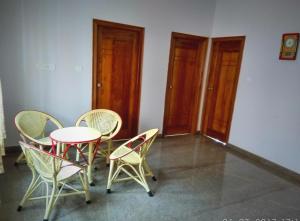 a table and chairs in a room with doors at Aashraya Homestay in Mysore