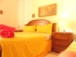 a bedroom with a bed with yellow and red pillows at Amabile Guesthouse in Milis
