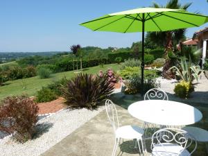 a table and chairs with a green umbrella at Studio Bel Air in Pimbo