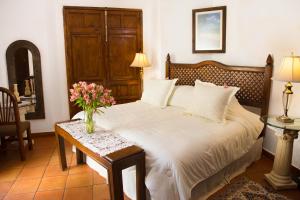 Un dormitorio con una cama y una mesa con flores. en Casa de Siete Balcones Hotel Boutique en Oaxaca de Juárez