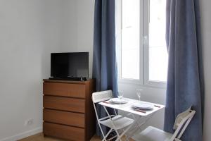 パリにあるPick a Flat's Apartment in Montmartre - Rue des Martyrs studioの小さなテーブル(椅子2脚付)、テレビが備わります。