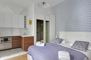 a bedroom with a large bed and a kitchen at Pick a Flat's Apartment in Montmartre - Rue des Martyrs studio in Paris