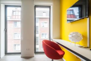 Habitación con silla roja y pared amarilla en Ooostel2.be Leuven, en Lovaina
