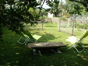 eine Bank und zwei Gartenstühle im Hof in der Unterkunft Il Barucin in Villar San Costanzo