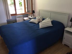 Una cama azul con almohadas y un osito de peluche. en La Maison D'ILHAN, en Ilhan