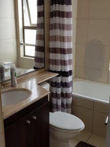 a bathroom with a toilet sink and a shower curtain at Mar Egeo in Iquique