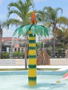 a statue of a bird sitting on top of a palm tree at Grand Palladium Imbassaí Resort & Spa - All Inclusive in Imbassai