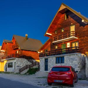 una macchina rossa parcheggiata di fronte a una casa di Guesthouse Wolf a Žabljak Altre 37 foto