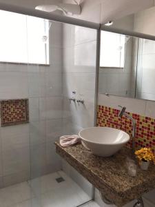 La salle de bains est pourvue d'un lavabo et d'une douche en verre. dans l'établissement Hotel do Reinildo I, à Cachoeira Paulista