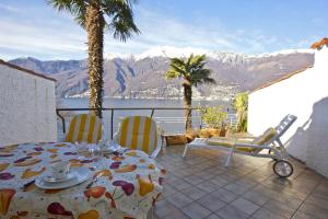 een tafel en stoelen op een patio met uitzicht op de bergen bij Casa Roccia in Pino Lago Maggiore