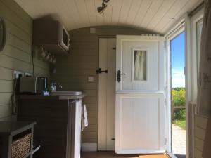 a door leading to a kitchen with a microwave at Shepherd's Hut at Puttocks Farm in Great Dunmow