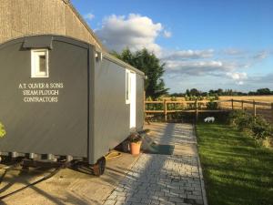 a trailer is parked next to a building at Shepherd's Hut at Puttocks Farm in Great Dunmow