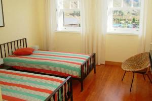 - une chambre avec deux lits, une chaise et deux fenêtres dans l'établissement Quinta das Mineirinhas, à Vila Nova de Cerveira