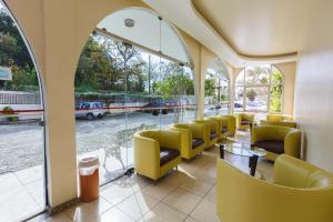 una sala de espera con sillas amarillas, mesas y ventanas en Tri Hotel Florianópolis en Florianópolis