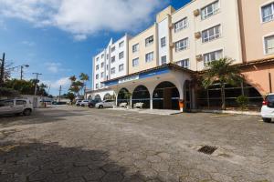 un gran edificio con coches estacionados en un estacionamiento en Tri Hotel Florianópolis en Florianópolis