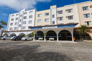 un grand bâtiment blanc avec des voitures garées dans un parking dans l'établissement Tri Hotel Florianópolis, à Florianópolis