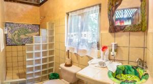 a bathroom with a toilet and a sink and a window at Tierra de Sueños Lodge & Wellness Center in Puerto Viejo