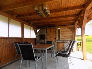 a patio with a table and chairs under a roof at Domki Nad Stawem Mazury D4 in Mrągowo
