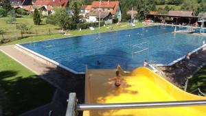 a large swimming pool with a yellow slide at Kleines Haus am Wald in Benshausen