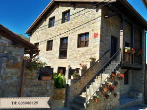 un antiguo edificio de piedra con macetas y escaleras en Apartamentos San Antonio de Garabandal, en San Sebastián de Garabandal