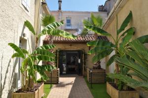 un patio de una casa con palmeras en Hôtel Le Loft, en Trie sur Baise