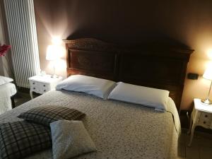 a bedroom with a bed with white pillows and two lamps at B&B Cascina Barolo in Turin