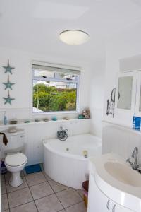 a bathroom with a tub and a toilet and a sink at Quarterdeck Holiday Apartment in Simonʼs Town