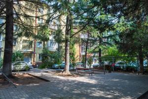 un parc avec bancs et arbres devant un bâtiment dans l'établissement Апартаменты на Ленина 54, à Adler