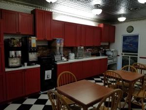 Prairie Inn في Vermillion: مطبخ مع دواليب حمراء وطاولة وكراسي