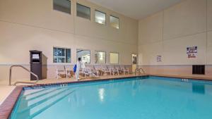 a swimming pool in a building with chairs around it at Best Western Plus Gas City in Gas City