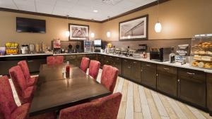 a restaurant with a wooden table and red chairs at Best Western Plus Kingston Hotel and Conference Center in Kingston