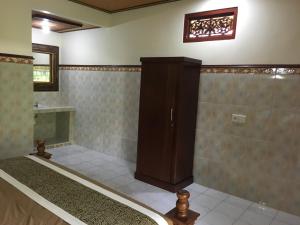 a room with a bed and a cabinet on the wall at Eka's Homestay in Ubud