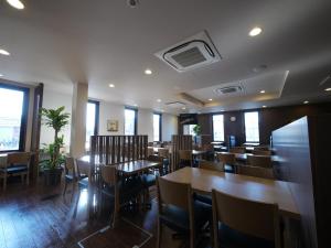 a restaurant with wooden tables and chairs and windows at Hotel Route-Inn Tome in Tome