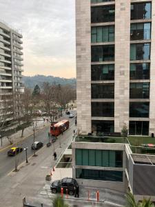 una calle de la ciudad con un autobús rojo delante de un edificio en Apartamento Costanera 106, en Santiago