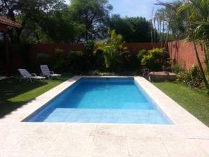 a swimming pool in a yard with two chairs at Hotel La Casona in Refineria Camiri