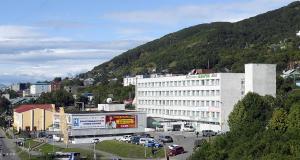 a large white building in front of a mountain at Hostel Avacha in Petropavlovsk-Kamchatskiy