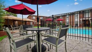 a table with chairs and an umbrella next to a pool at Best Western Parkway Inn & Conference Centre in Cornwall