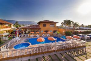 una piscina con sillas y sombrillas frente a una casa en Hotel Pousada Paradise, en Caraguatatuba