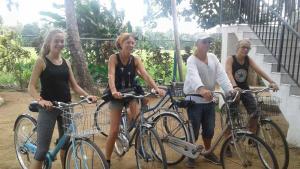 un grupo de cuatro mujeres de pie con sus bicicletas en Man Guest Polonnaruwa en Polonnaruwa