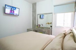 una camera da letto con un letto e una TV a parete di De Green Inn @aeropolis a Tangerang