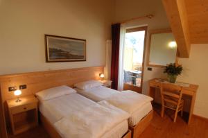 1 dormitorio con 2 camas, escritorio y ventana en Camping Dolomiti, en Dimaro