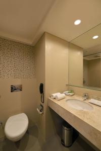 La salle de bains est pourvue d'un lavabo, de toilettes et d'un miroir. dans l'établissement Krishna Palace Hotel - Ambernath, à Amarnāth