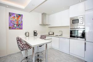 a kitchen with white cabinets and a counter with stools at Luxury Apartments with private swimming pool in Marbella