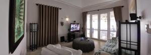 sala de estar con muebles blancos y TV en The Boathouse vietnam en Mui Ne